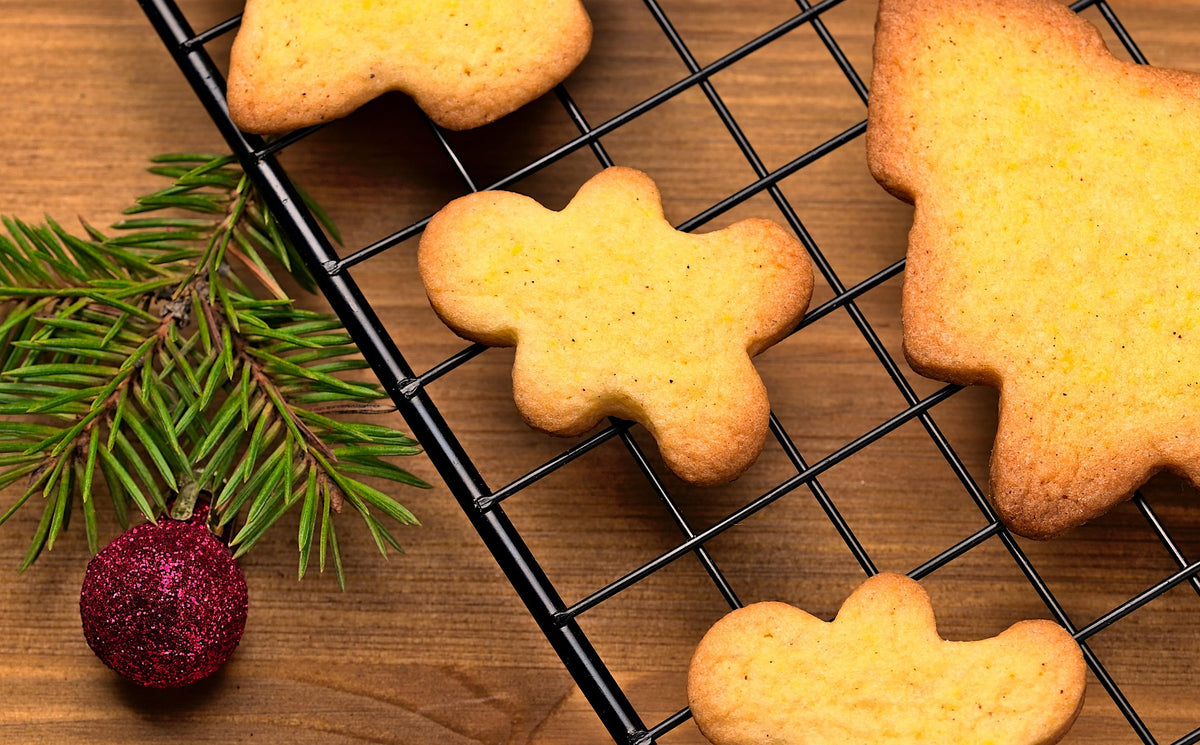 Weihnachtliche Kekse auf einem Gitter mit Tannenzweig und Christbaumkugel